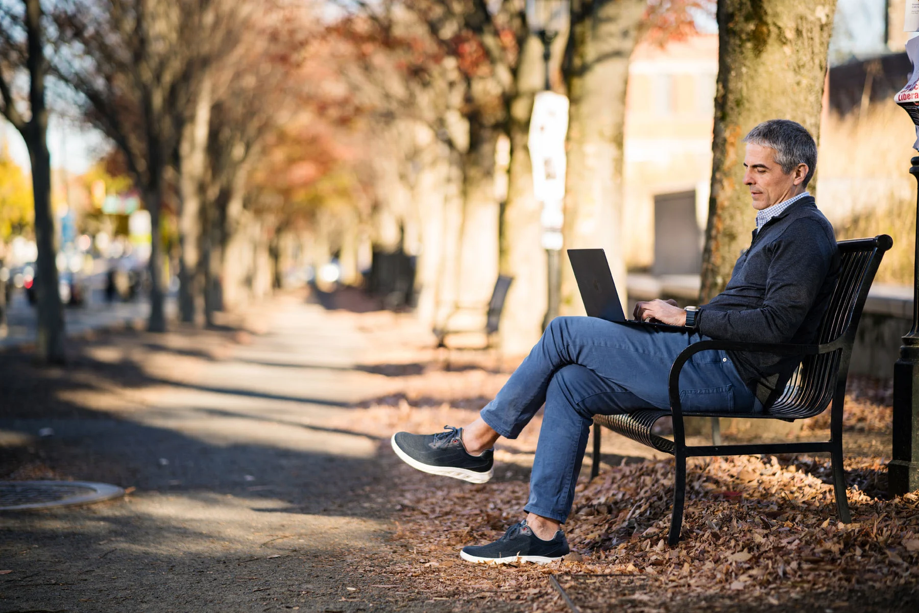Doug working on his laptop on a park bench
